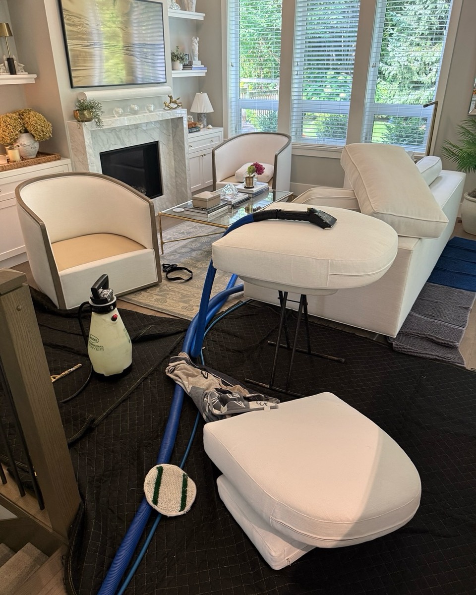 Sofa cushions being steam-cleaned in a bright luxury Vancouver living room with a marble fireplace